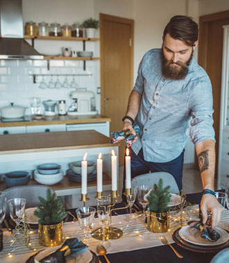 Mann mit Bart deckt einen Tisch auf dem Kerzen stehen